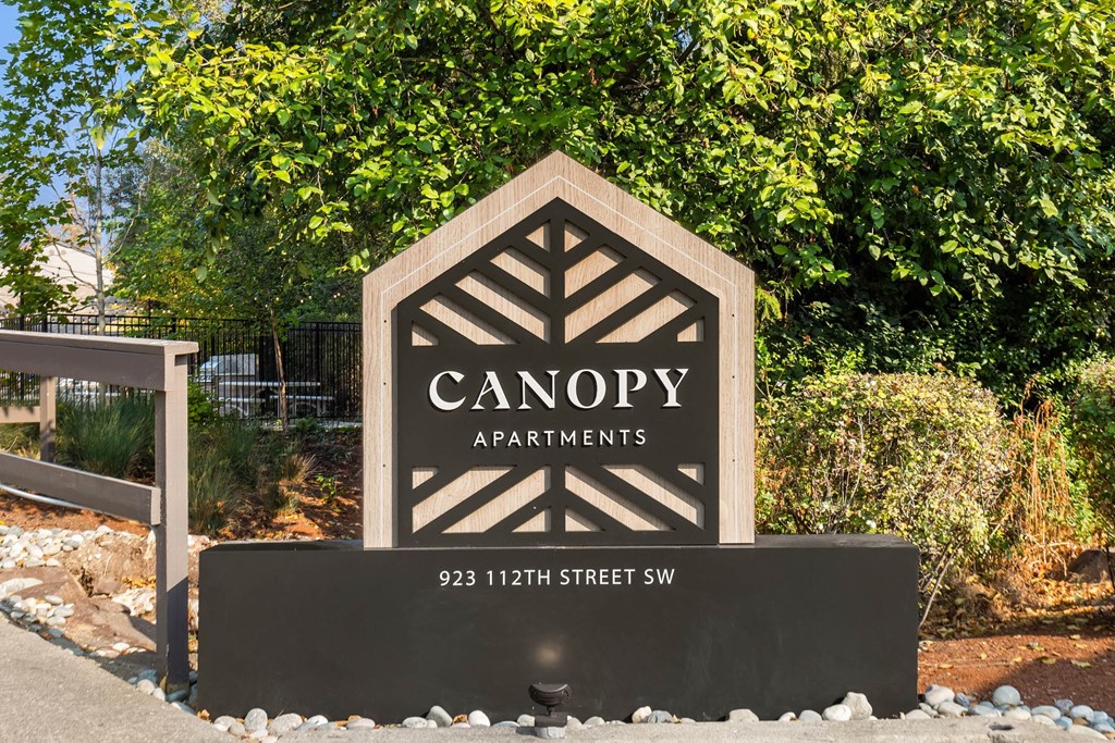 a sign for canopy apartments in front of trees