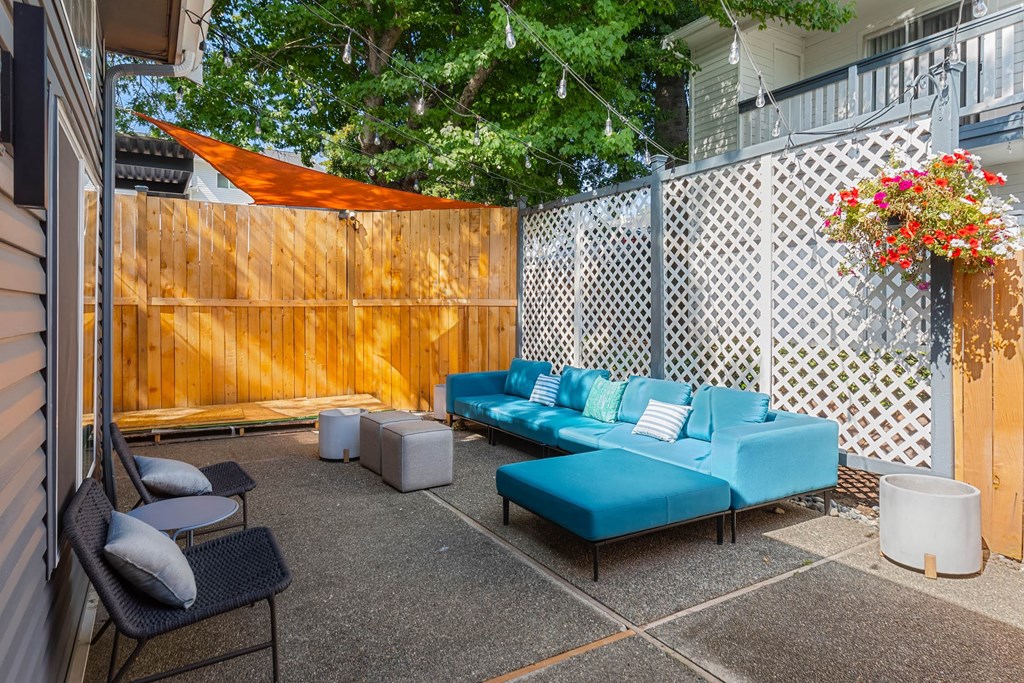 A blue couch is in the middle of a patio with a white table and chairs.