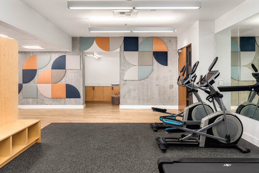 a gym with cardio equipment and paintings on the wall