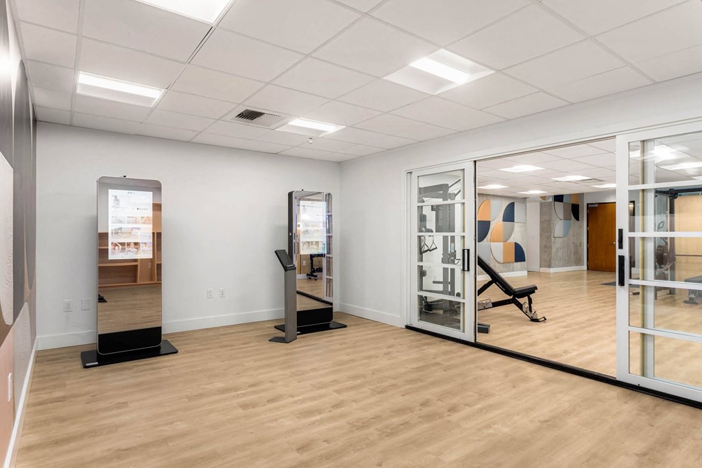 a fitness room with mirrors and a wood floor