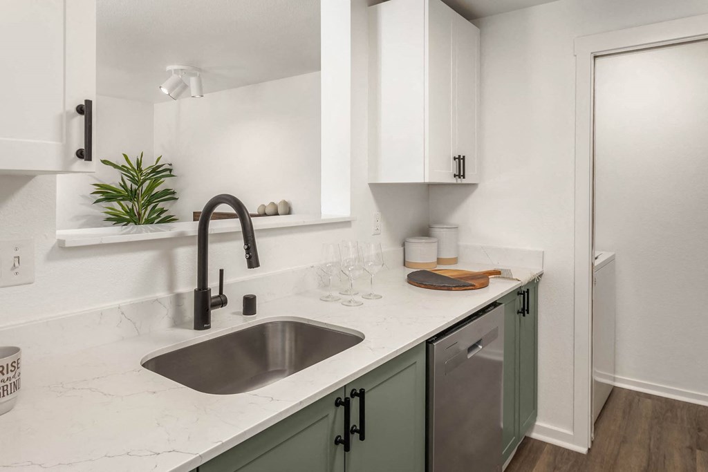 a kitchen with green cabinets and white countertops