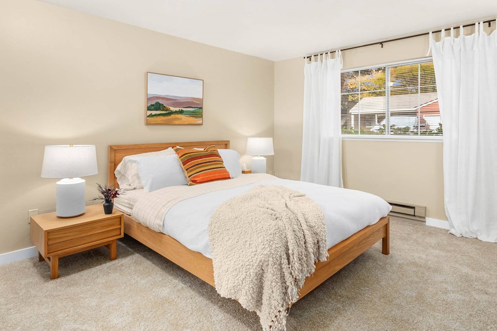 a bedroom with a bed and a window with white curtains