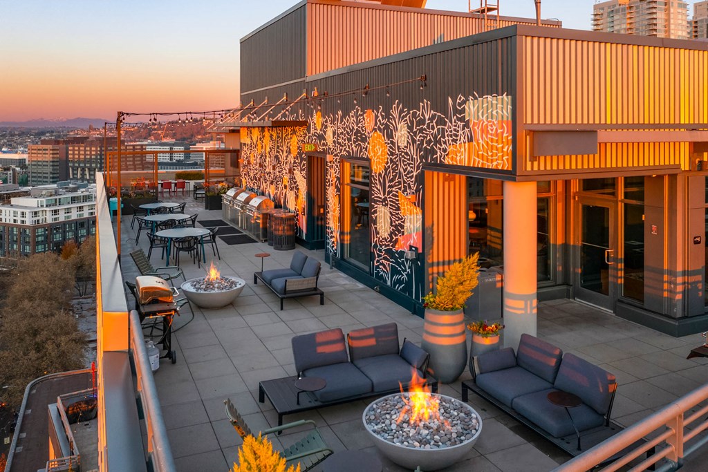 a rooftop terrace with couches and tables and fire pits