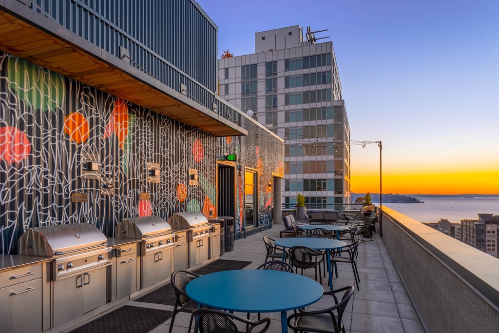 a terrace with tables and chairs and a view of the ocean and a building