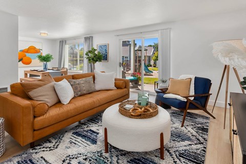 a living room with a couch chair and ottoman in front of a sliding glass door