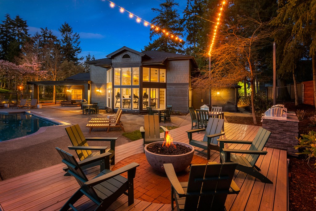 a backyard with patio furniture and a fire pit at night