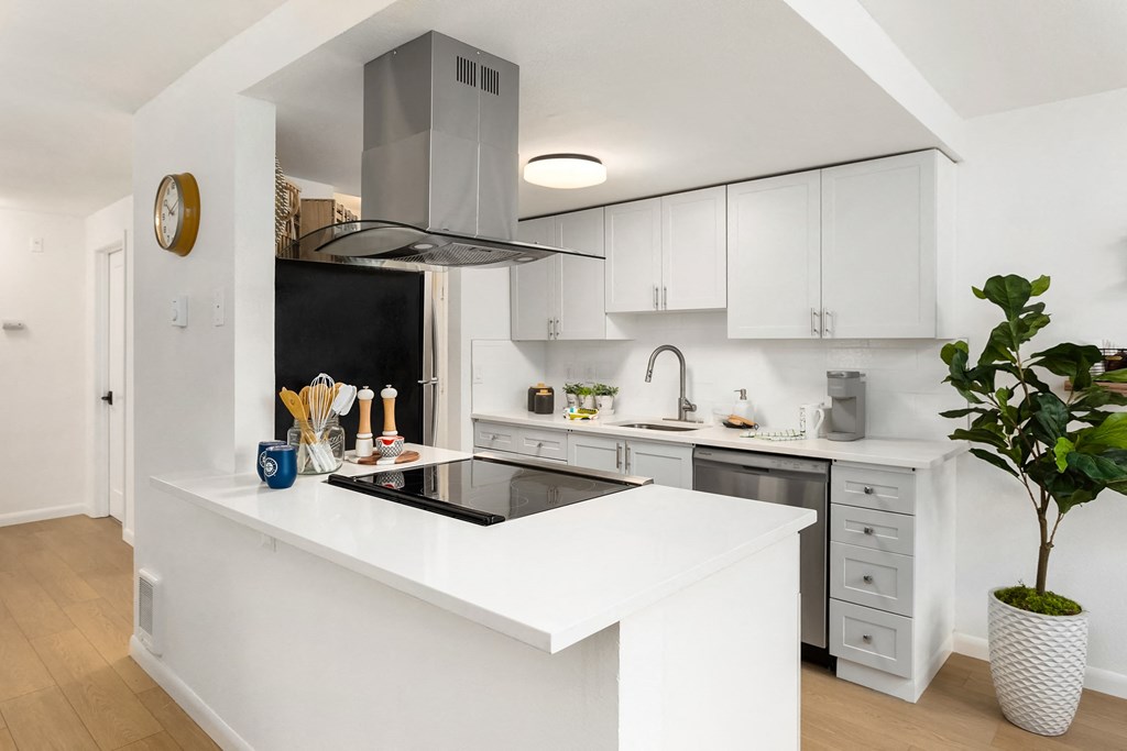 a white kitchen with a large island and a black stove