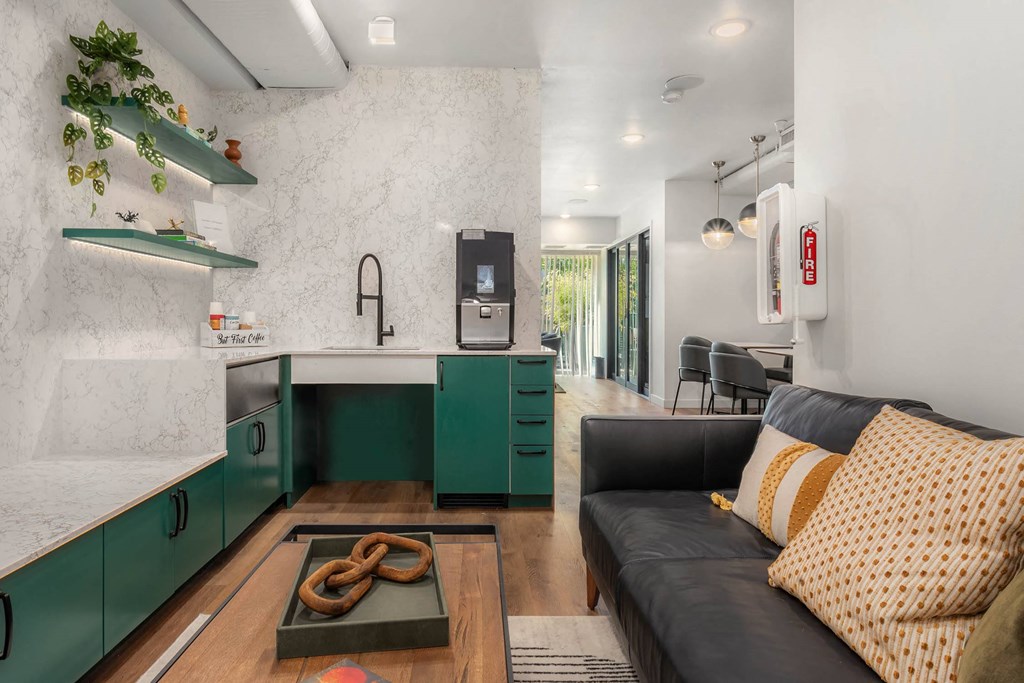 a living room with a couch and a kitchen with green cabinets