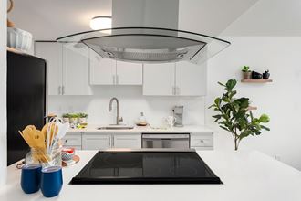 a white kitchen with a black stove and a white counter top