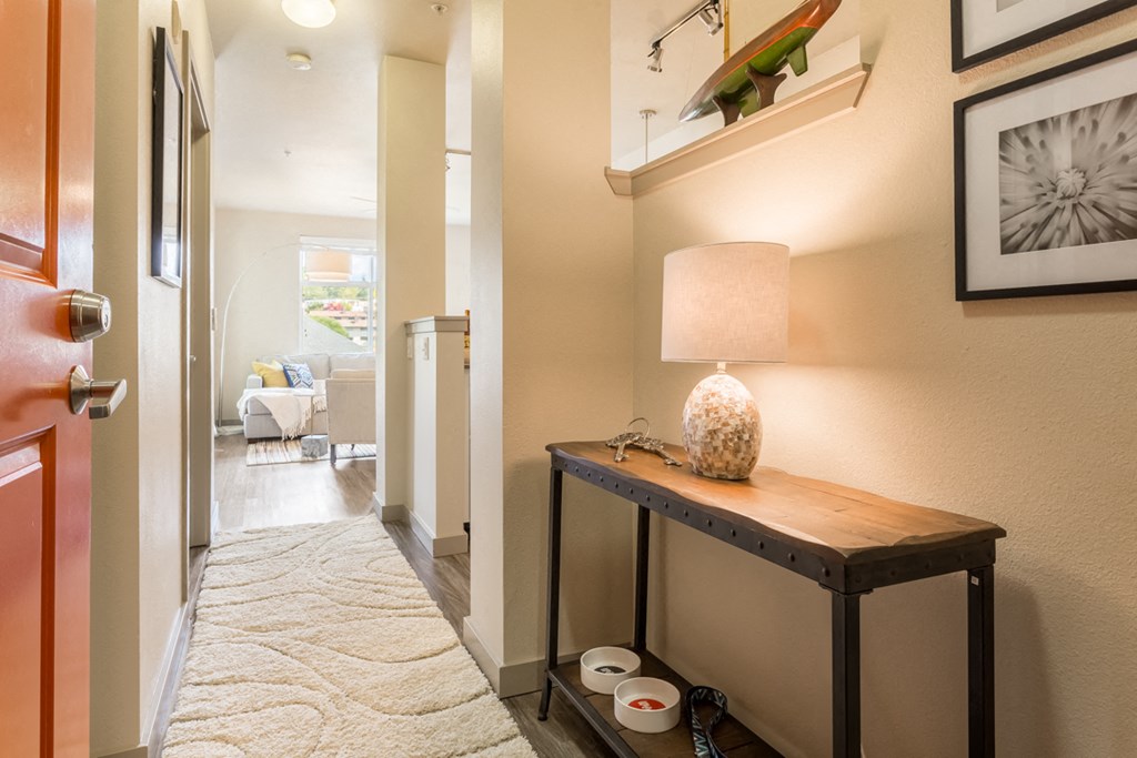 a hallway with a table with a lamp and a rug