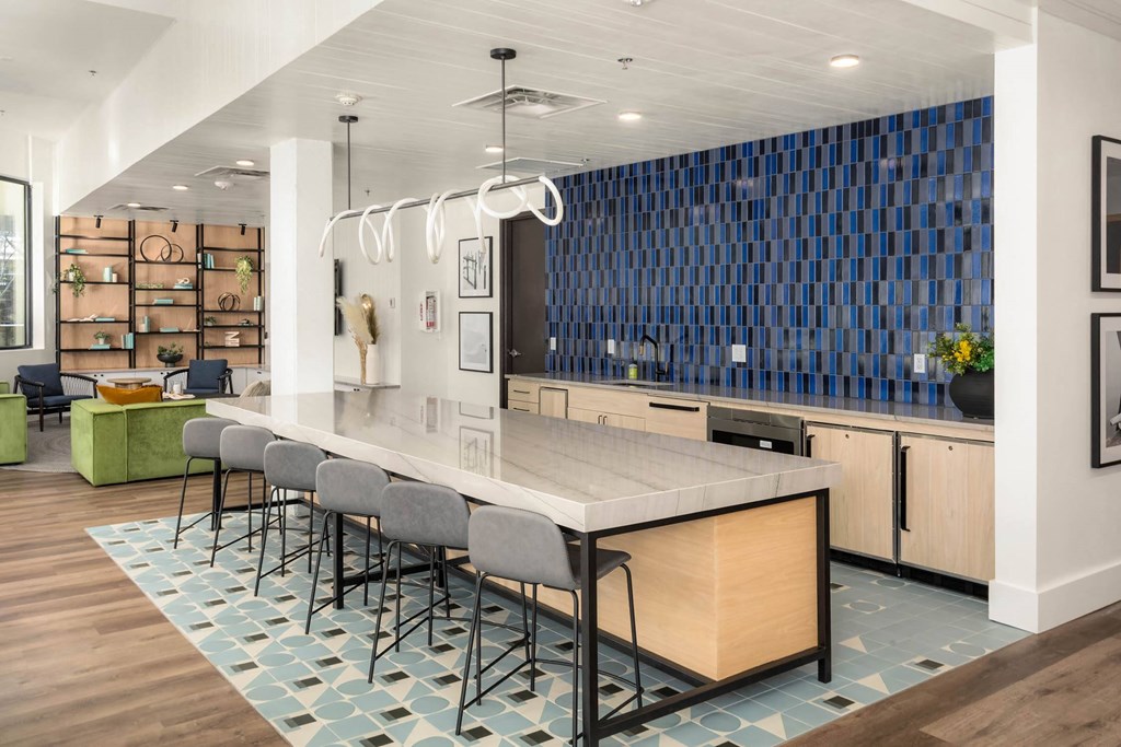 a kitchen with a long island with a white countertop and a long blue tile wall