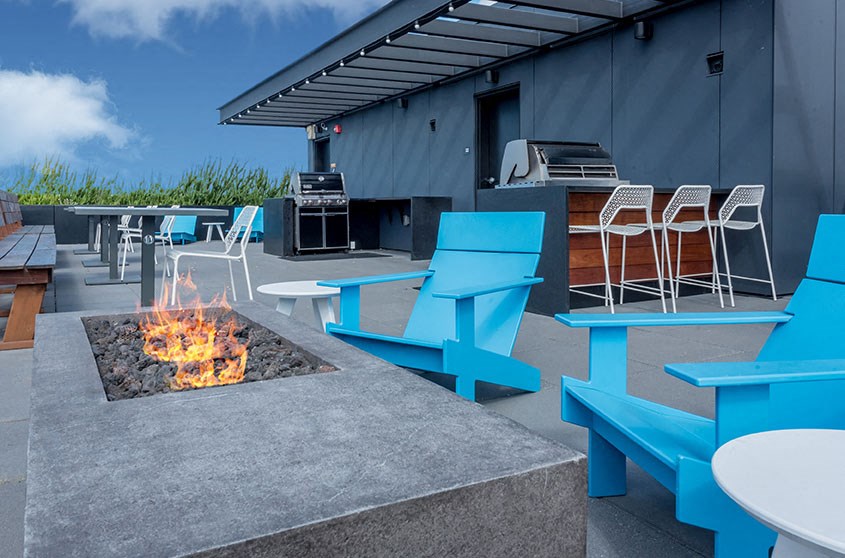 a patio with blue chairs and a fire pit