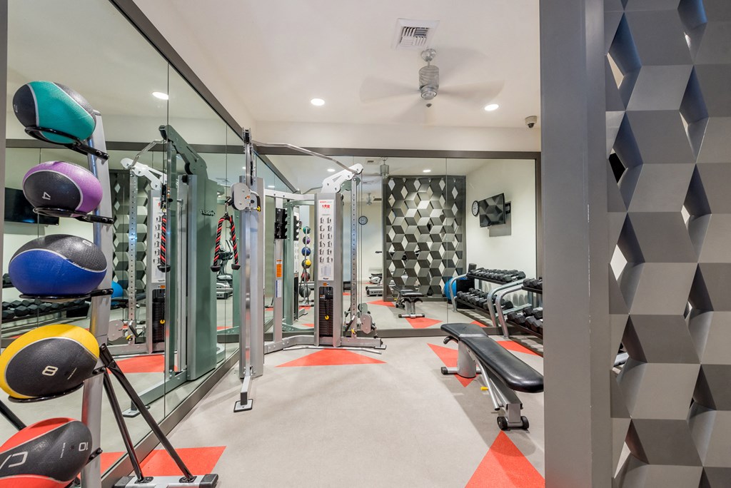 a gym with weights and cardio equipment and a geometric wall in the back