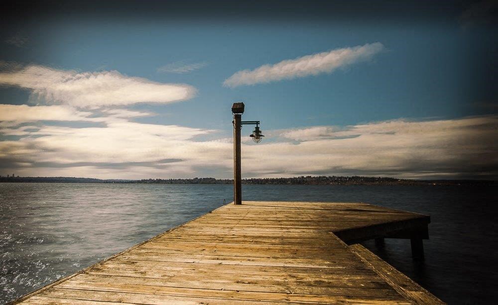 a wooden dock with a lamp post on the water