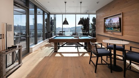A room with a pool table and chairs.