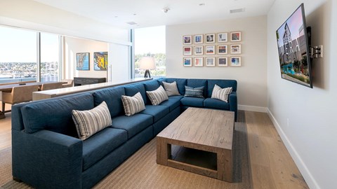 A living room with a blue couch and a television on the wall.