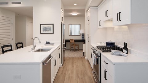 A modern kitchen with white cabinets and a wooden floor.