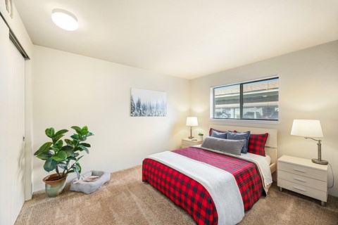 A bedroom with a red and black checkered bedspread.