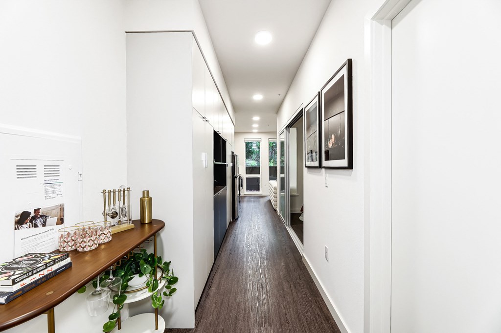 a long hallway with white walls and a wooden floor and a hallway with a counter