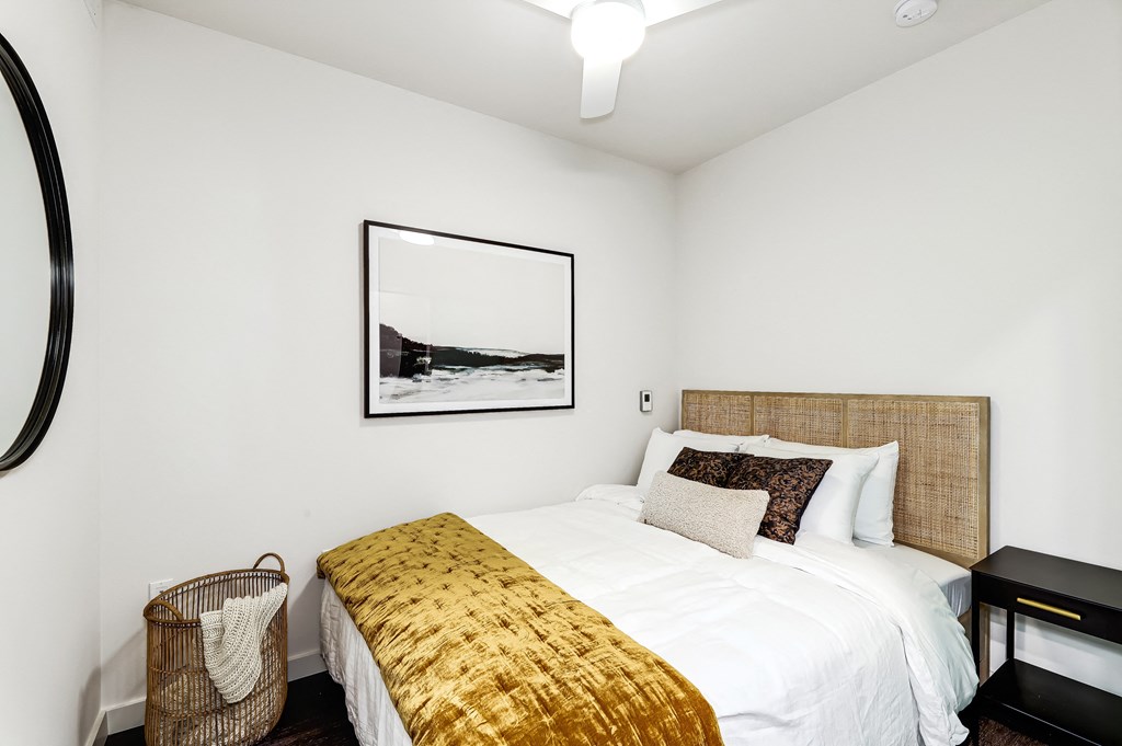 a bedroom with white walls and a bed with a gold blanket