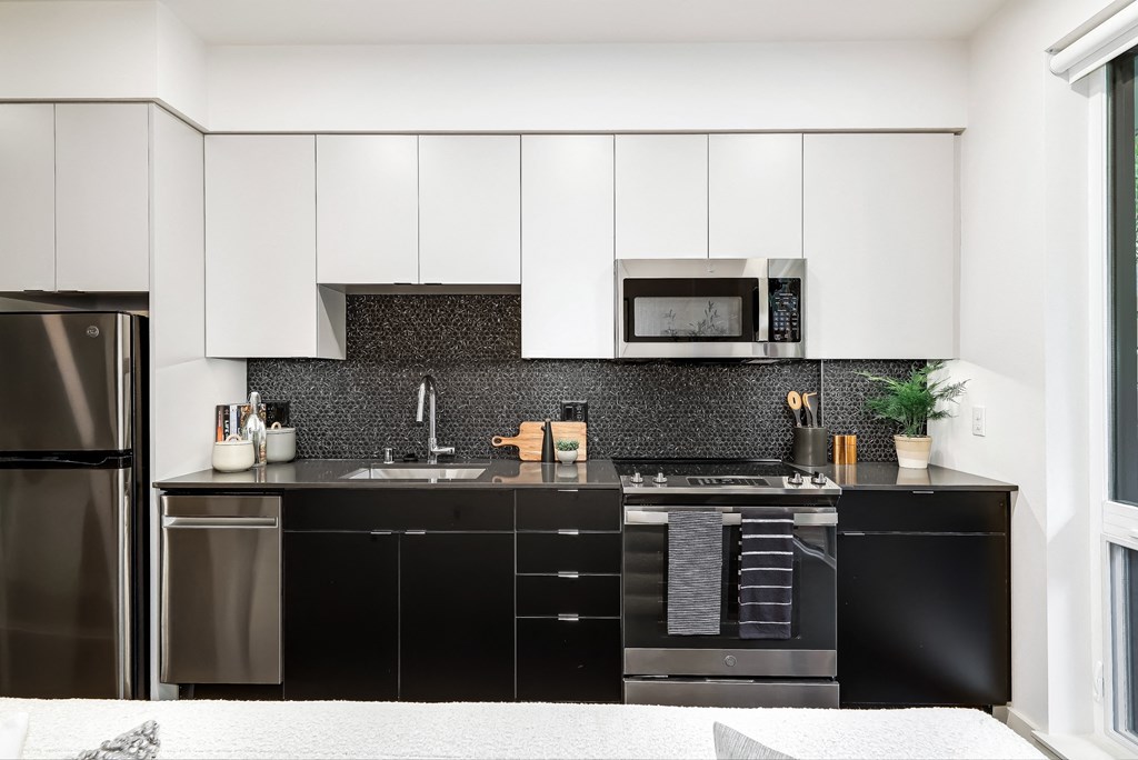 a modern kitchen with black and white cabinets and stainless steel appliances