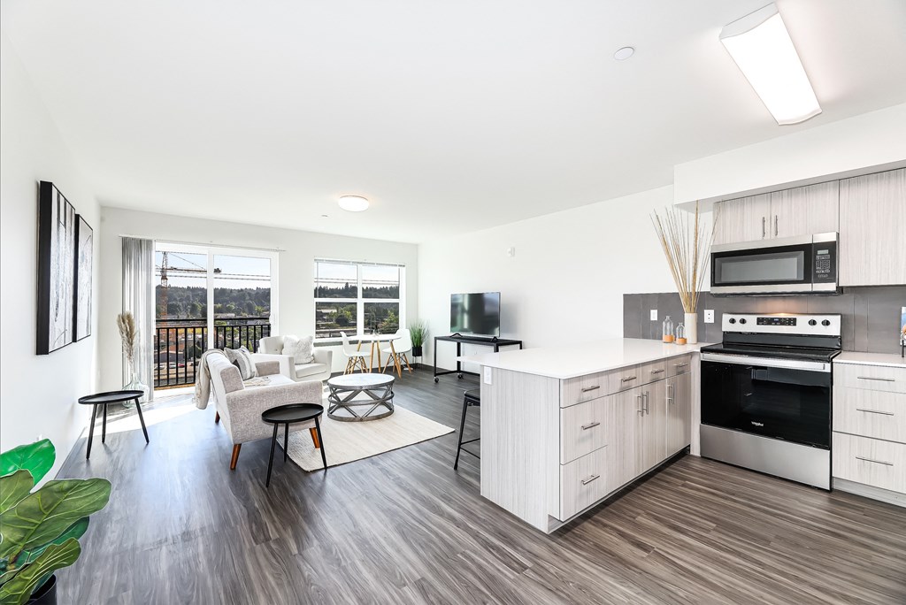 a living room with a kitchen and a balcony