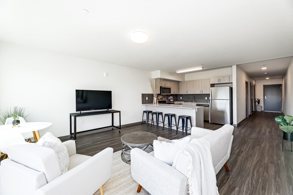 a living room and kitchen with white furniture and a tv