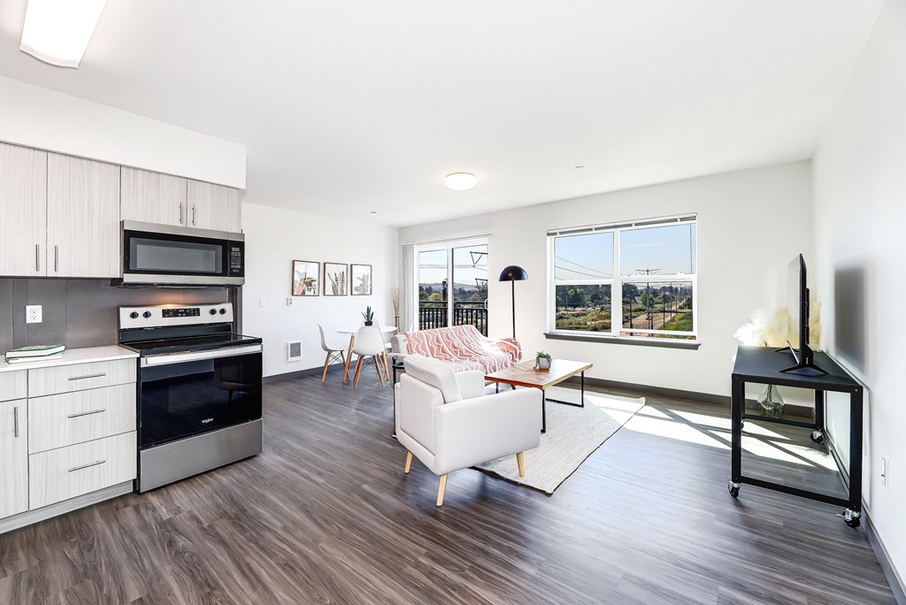 a living room with a couch and a kitchen with a stove and a microwave