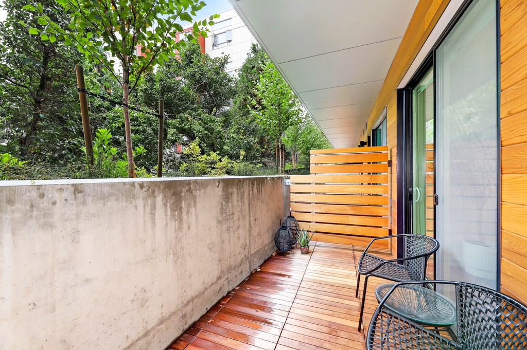 a balcony with chairs and a wooden privacy fence