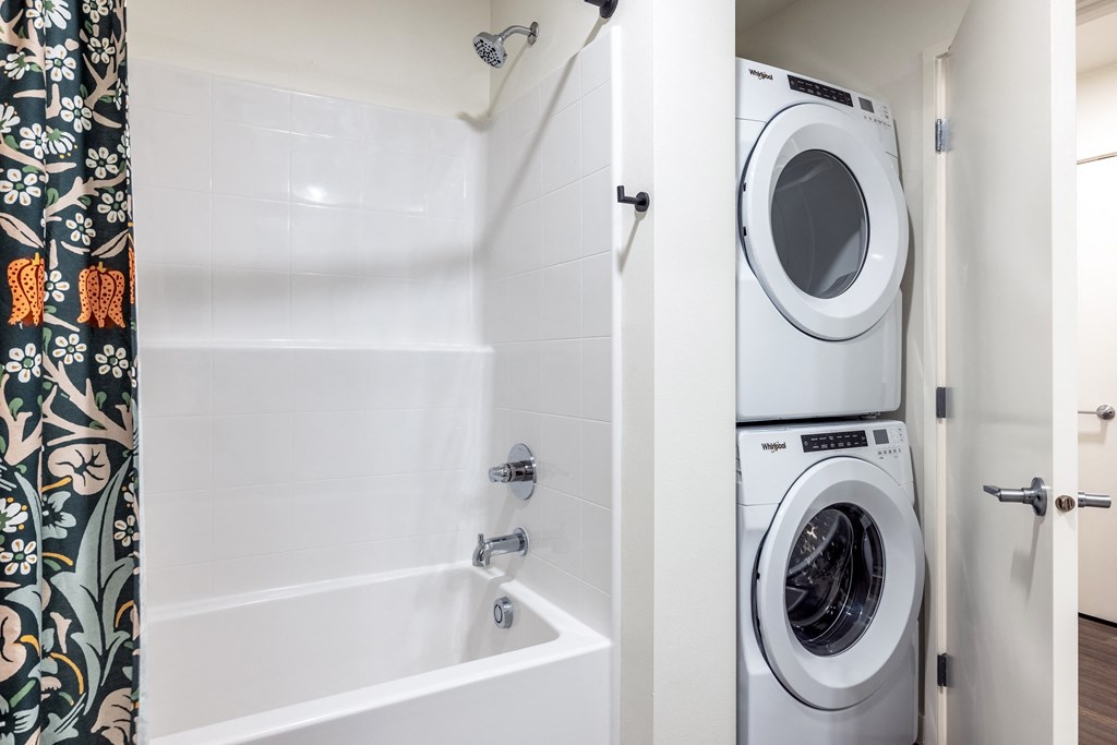 a washer and dryer in a bathroom next to a shower and a tub