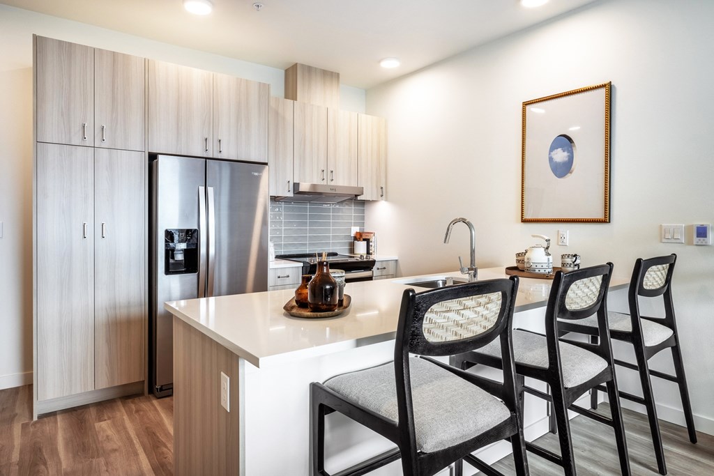 a kitchen with a island with three chairs and a refrigerator
