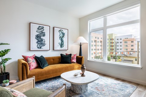 A living room with a yellow couch and two framed artworks on the wall.