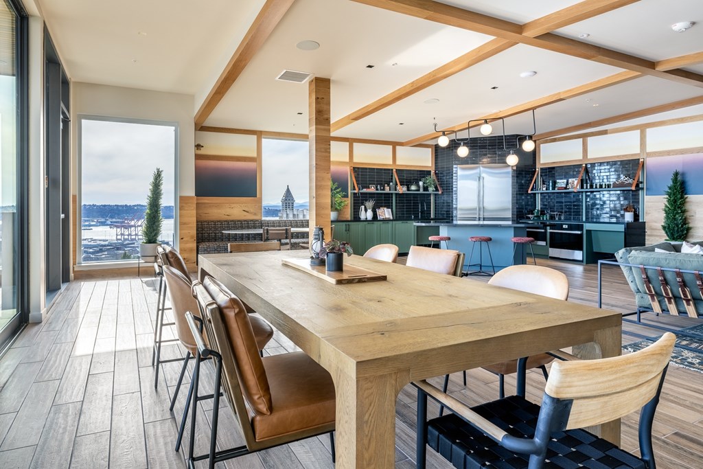 A long wooden table with chairs is in the middle of a room with a view of the water.