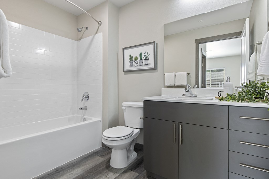 A white toilet sits next to a white bathtub in a bathroom.