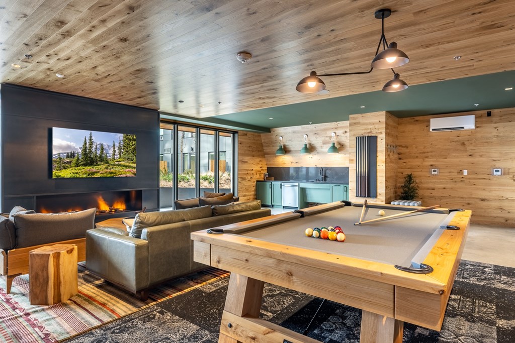 A billiard table is in the middle of a room with a fireplace and a couch.