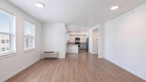 A spacious room with wooden flooring and white walls.