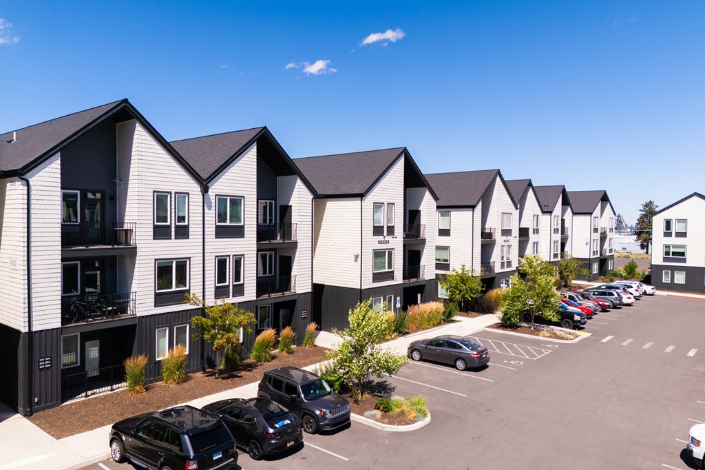A row of modern townhouses with cars parked in the driveway.