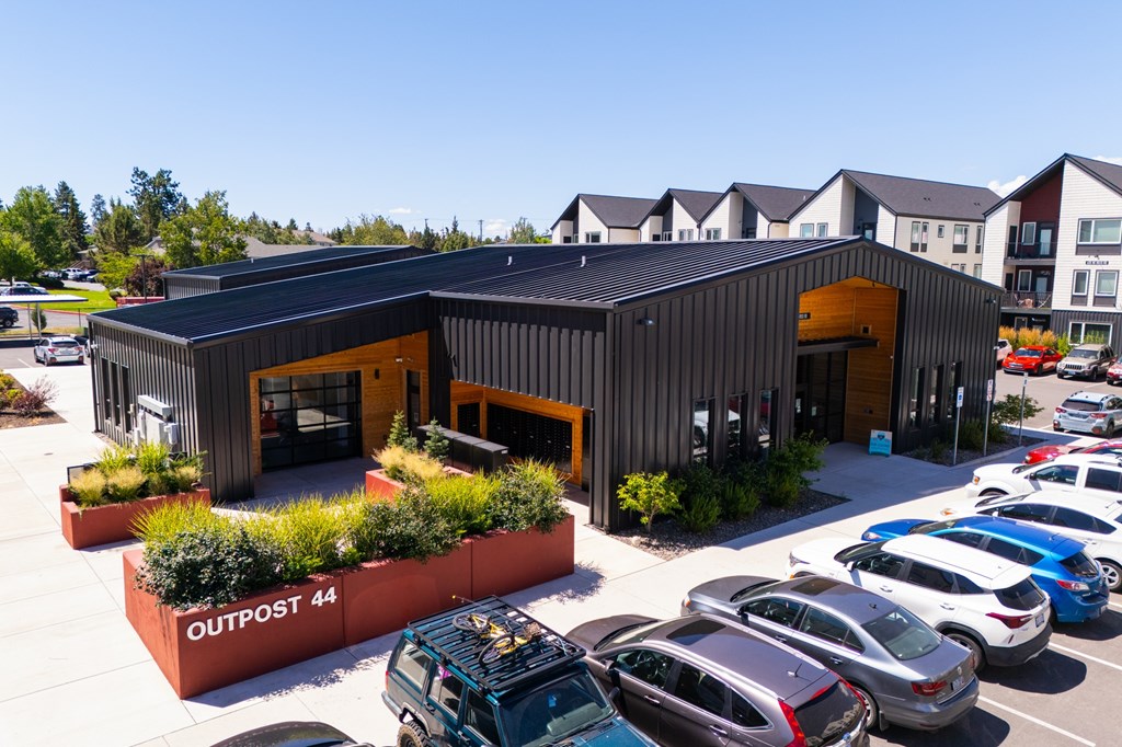 A parking lot with cars and a building with the sign OUTPOST 44.