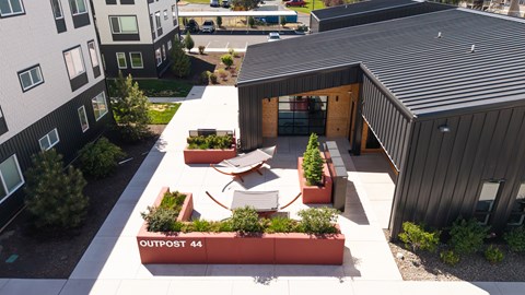 A modern building with a black roof and a sign that says "OUTPOST 44" in front of it.