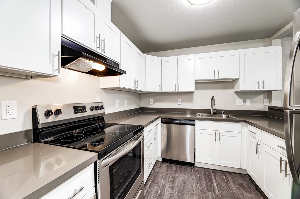 an empty kitchen with white cabinets and stainless steel appliances
