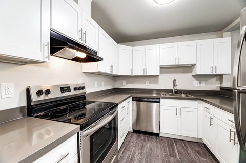 an empty kitchen with white cabinets and stainless steel appliances