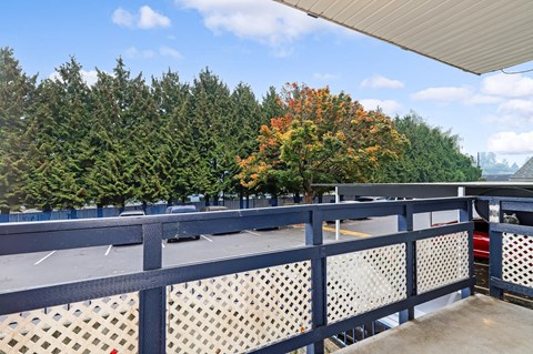 a balcony with a view of a parking lot and trees