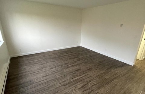 A room with wooden flooring and white walls.