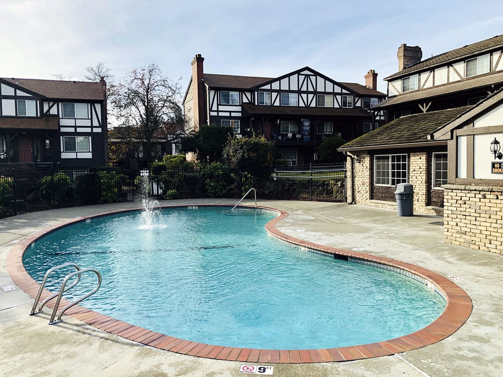 a large pool with a fountain in front of a house