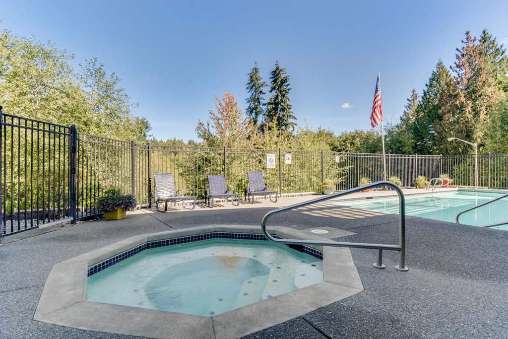 a hot tub and a pool with a fence and an flag