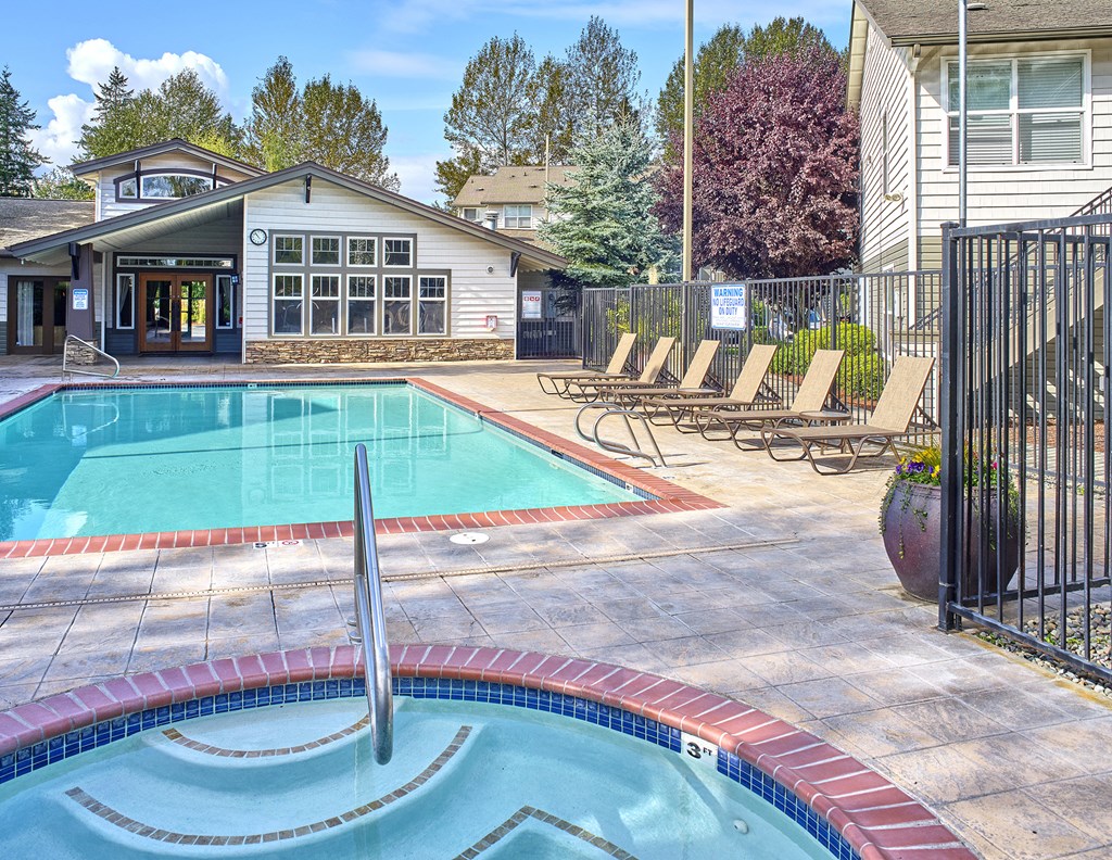 a swimming pool with chaise lounge chairs in front of a house