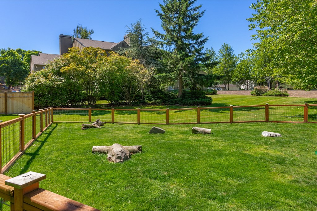 a backyard with a fenced in area with grass and rocks