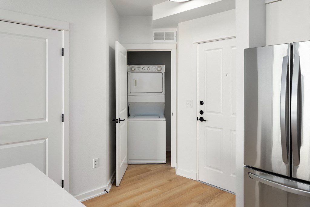 an empty kitchen with a refrigerator and a washer and dryer