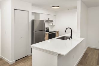 a renovated kitchen with an island and stainless steel refrigerator