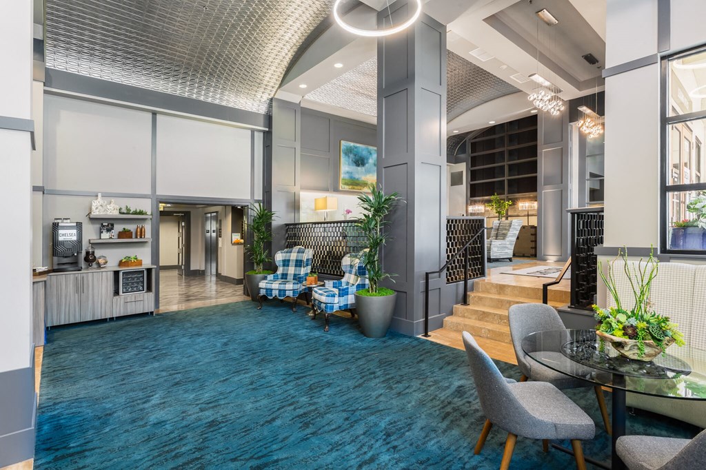 a lobby with a blue carpet and chairs and a staircase